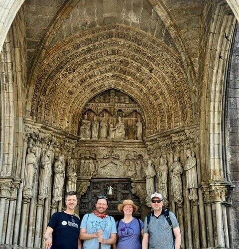 Friends standing beneath an ornate stone cathedral entrance on the Camino de Santiago during a 12 day Galicia and Portugal trip with Eat & Walkabout.