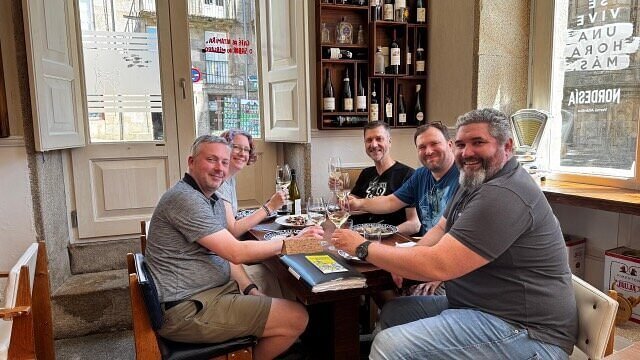 Group enjoying a shared meal and wine as part of an Eat & Walkabout Galicia and Portugal experience.