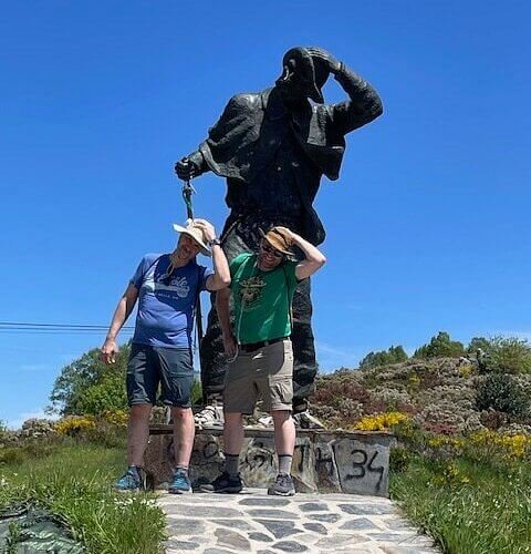 Hikers posing beside a pilgrim statue during a guided Eat & Walkabout Camino walk.